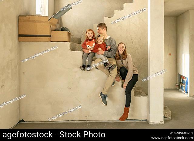 Happy family sitting on staircase at incomplete home