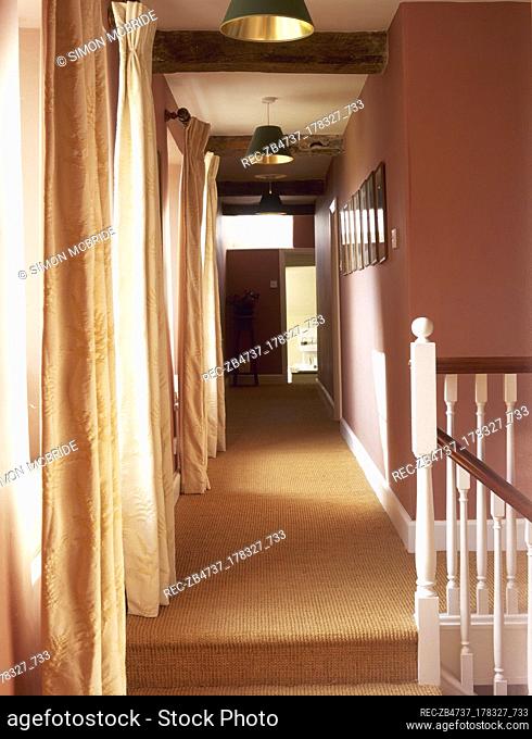 Carpeted stairway landing and hallway with terracotta colour walls