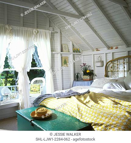 BEDROOM - Vacation home. Painted white walls. Brass bed, exposed beams, exposed lath walls painted white, yellow and white checked quilt, green antique trunk