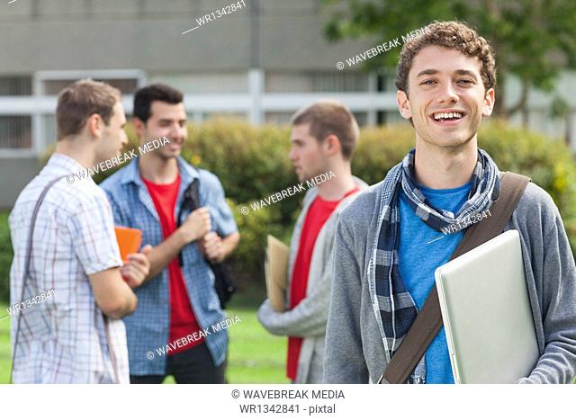 Cheerful student smiling at camera in front of his classmates