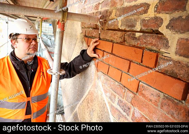02 May 2023, Saxony, Jocketa: Construction manager Seweryn Fic checks newly laid bricks in the more than 150-year-old Elster Valley Bridge in the Vogtland...
