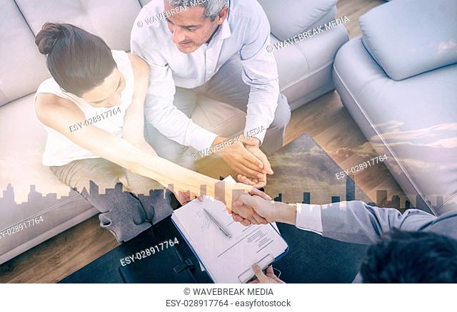 Businesswoman doing handshake with a businessman sitting on sofa