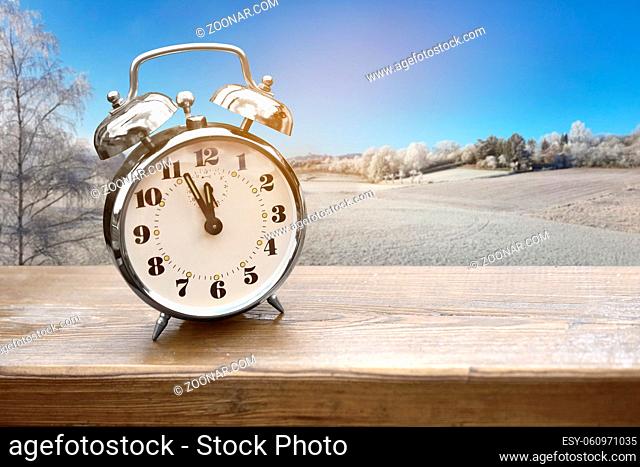 Alarm clock on wooden board just before the winter beginning