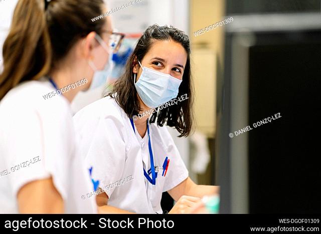 Close-up of female doctors wearing masks discussing while sitting in hospital