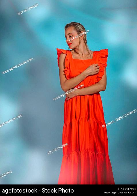Beautiful Woman Wearing Long Red Dress Over Abstract Background. Studio Shot. Luxury Fashionable Dress