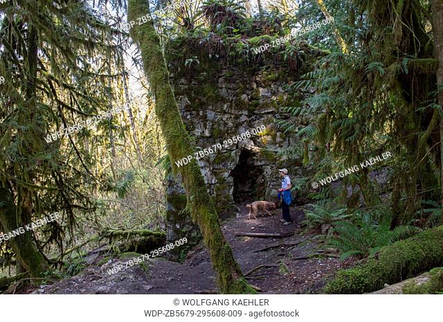 Hiker (Model Release 20020923-10) with dog (Miniature Golden doodle) on the Lime Kiln Trail looking at the historic kiln near Granite Falls, Washington State