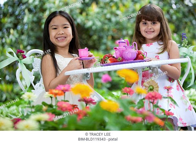 Mixed race girls having tea party in backyard
