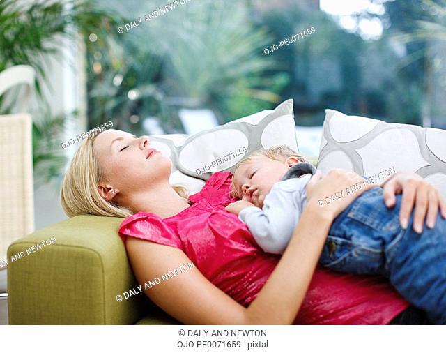 Woman napping on sofa with baby boy