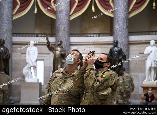Members of the National Guard take photos in Statuary Hall of the U.S. Capitol, as the House of Representatives vote on H. Res
