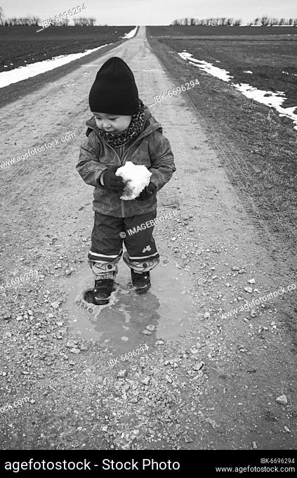 Toddler, boy, 18 months, multi-ethnic, steps in puddle, plays with snowballs, laughs, Blaubeuren, Baden-Württemberg, Germany, Europe