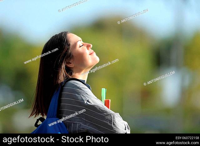 Side view portrait of a happy student breathing fresh air in a campus
