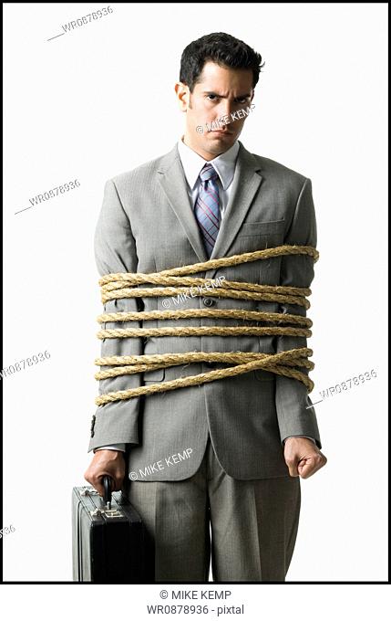 businessman in a full suit tied up with a rope around his mid section