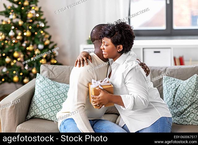 happy african couple with christmas gift at home