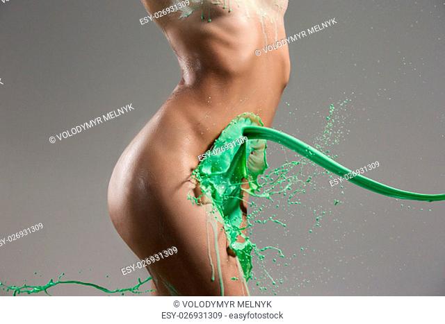 The beautiful woman with green liquid paint over her body on gray