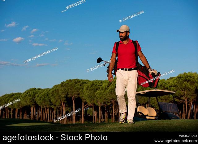 handsome middle eastern golfer carrying golf bag and walking at course to next hole
