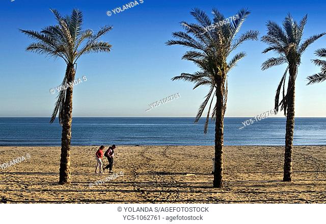 Couple walking on beach in winter, Cabopino, Costa del Sol. Marbella, Malaga province, Andalusia, Spain