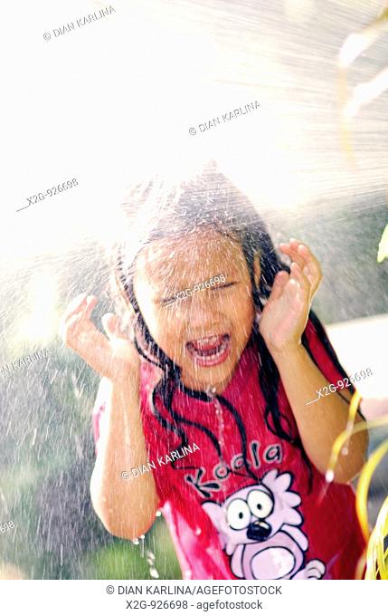 A little girl splashed wit h water from a hose pipe