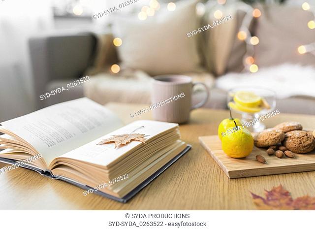 book, lemon, tea and cookies on table at home