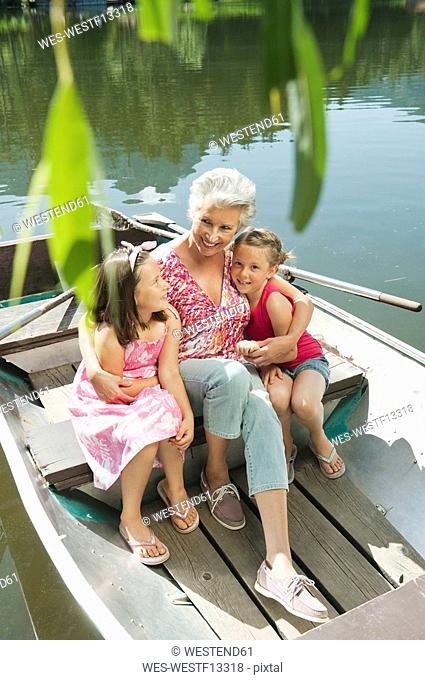 Italy, South Tyrol, Grandmother and grandchildren 6-7 8-9 sitting in rowing boat, elevated view, portrait