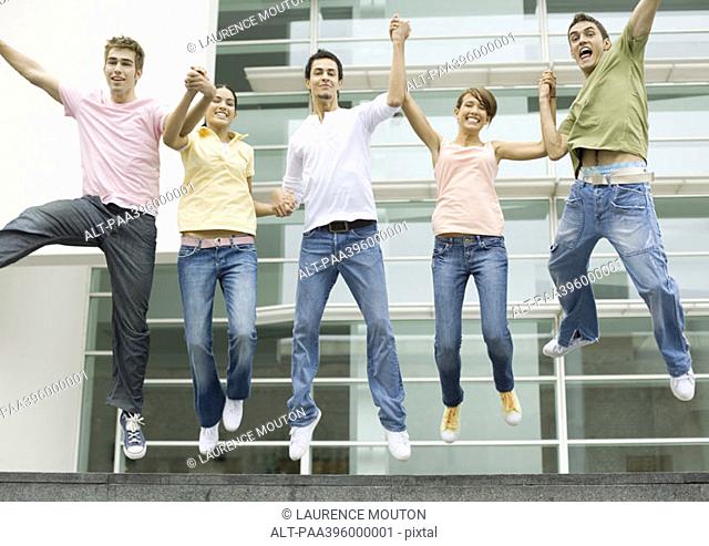 Teens holding hands and jumping in the air