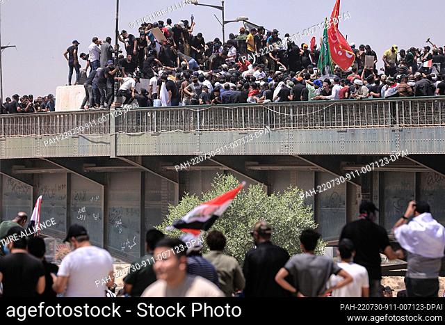 30 July 2022, Iraq, Baghdad: Supporters of Iraq's influential Shiite cleric Moqtada al-Sadr tear down the concrete barriers on Al-Jumhuriya before storming into...