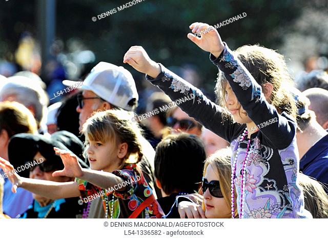 Young girl raises hands and arms in crowd during Gasparilla Pirate Festival Parade Tampa Florida