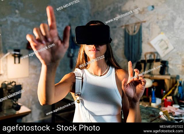 Businesswoman wearing virtual reality simulator gesturing at home