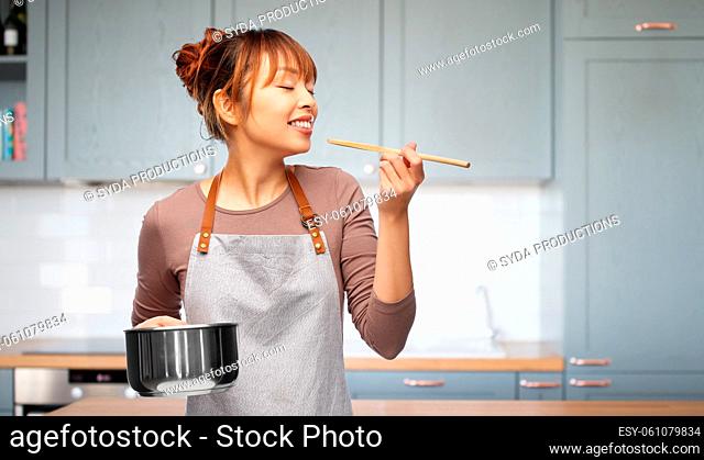happy woman in apron with saucepan in kitchen