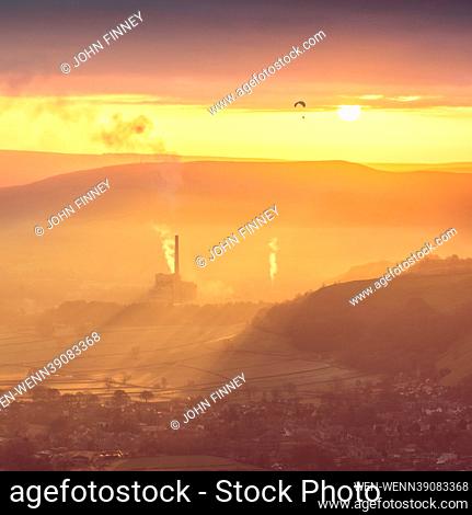 A stunning scene over Castleton village in the heart of the Peak District National Park with a powered a paraglider flying past the rising sun, Derbyshire