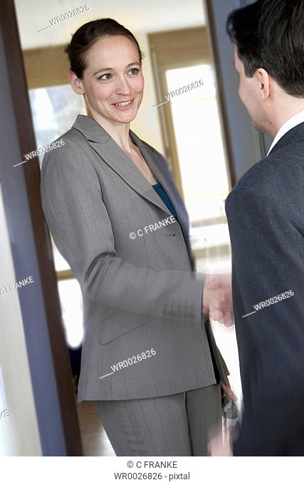 Businesswoman shaking hand with businessman at door