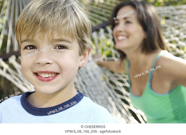 Portrait of a boy smiling with his mother in the background