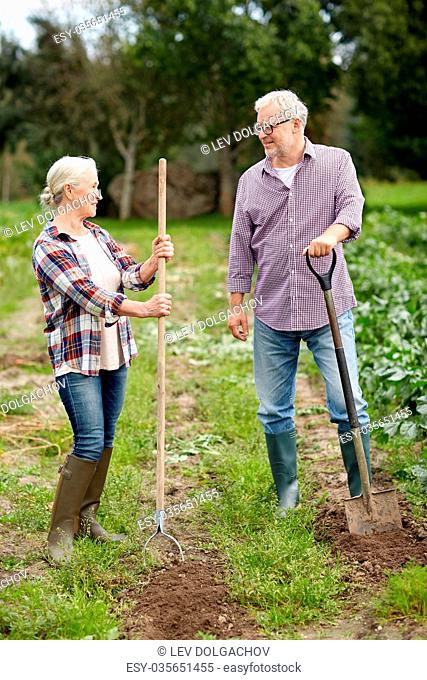 farming, gardening, agriculture and people concept - senior couple with shovels at garden or farm