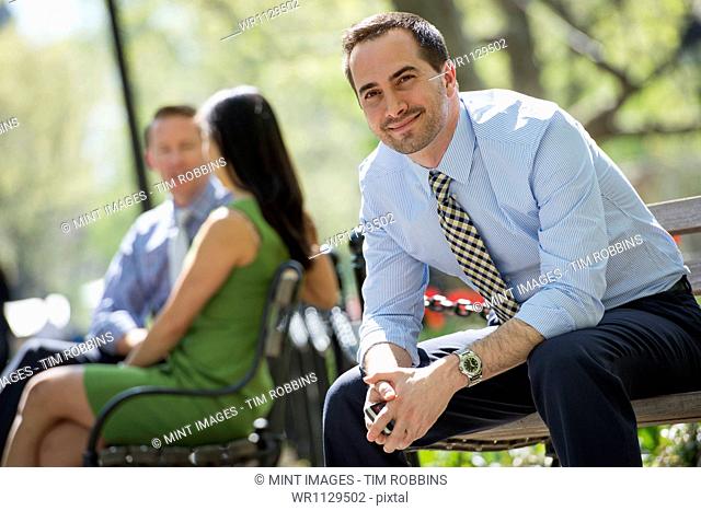 A small group of people, a businesswoman and two businessmen outdoors in the city