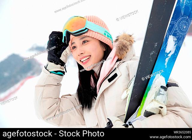 Skiing field holding the skis beautiful young woman