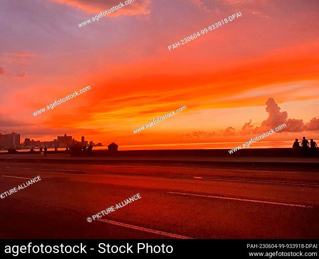 06 September 2022, Cuba, Havanna: At sunset, several people sit on the wall on the Malecón, the sea promenade, in the Cuban capital