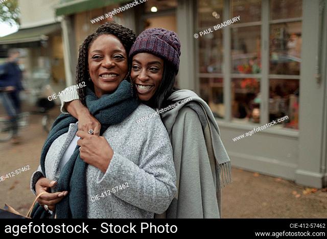 Portrait happy mother and daughter hugging on sidewalk