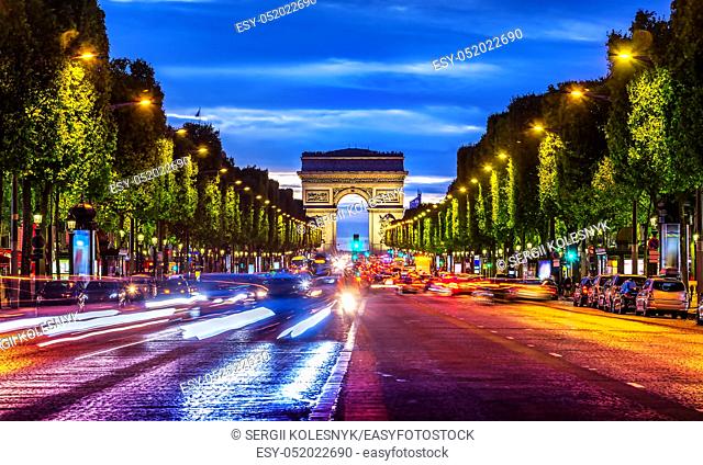 Illuminated Champs Elysee and view of Arc de Triomphe in parisian evening, France