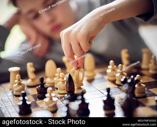 Boy holding chess piece while playing at home