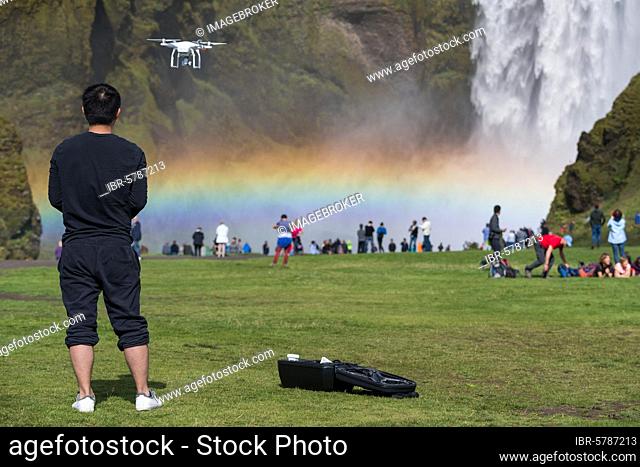 Man with drone in front of the big waterfall Skógafoss, Skogafoss, Skogar, Ring Road, Sudurland, South Iceland, Iceland, Europe