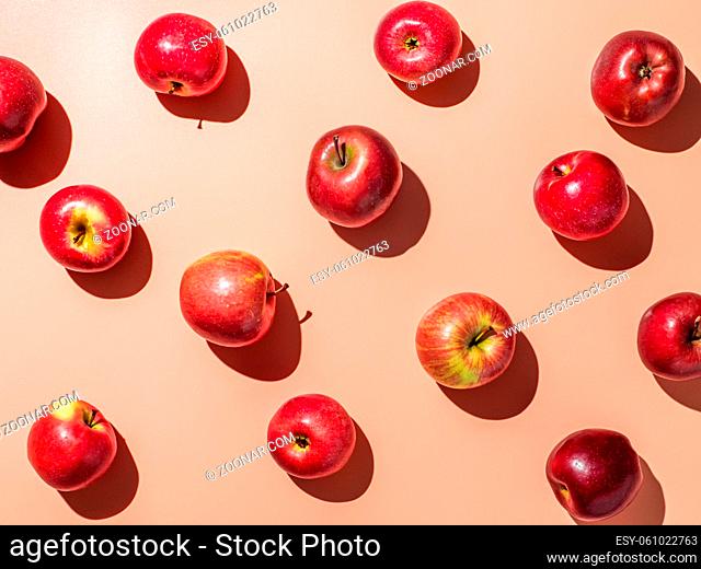 Delicious red apples on orange or coral pink background pattern. Colorful fruit frame. Flat lay or top view, Hard light. Creative concept
