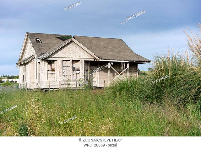 Abandoned single family home with wooden siding as fixer upper property