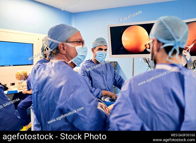 Surgeons wearing face mask having discussion while operating surgery in operation room