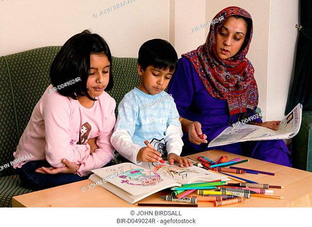 Single parent helping her young children with colouring book