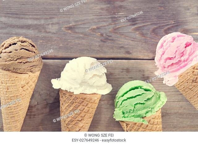 Chocolate, vanilla, matcha and strawberry ice cream in the cone on rustic wooden vintage background