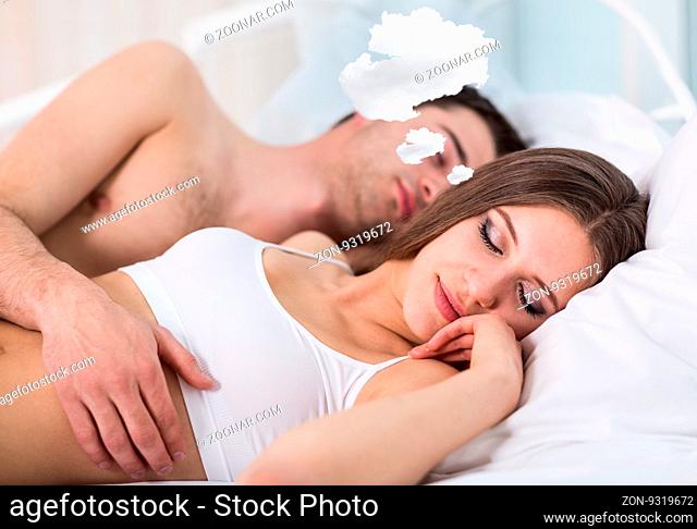 Woman with thoughts cloud sleeping in bed with her boyfriend