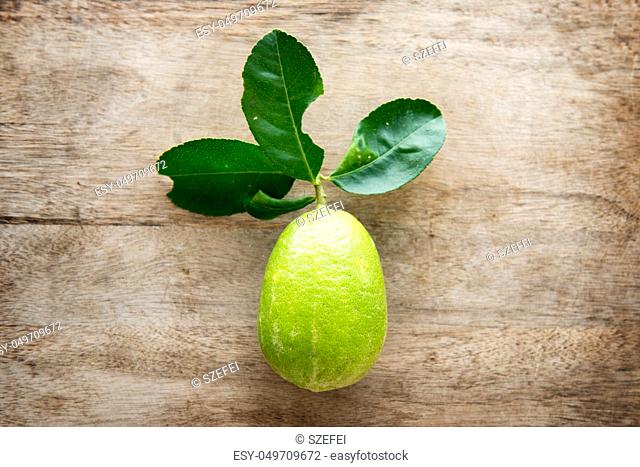 Top view fresh organic lemon with leaves on wooden table background, pesticide free, imperfect insect bites