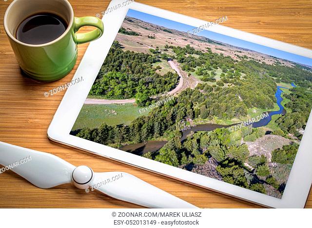 Dismal River in Nebraska Sandhills near Seneca, spring scenery - reviewing aerial image on a digital tablet with a cup of coffee