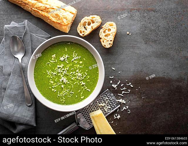 Fresh vegetable cream soup with parmesan cheese on grey background overhead shoot