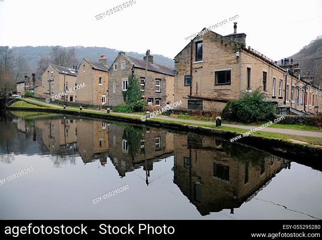streets of terraced houses alongside the rochdale canal in hebden bridge with reflections in the water in winter