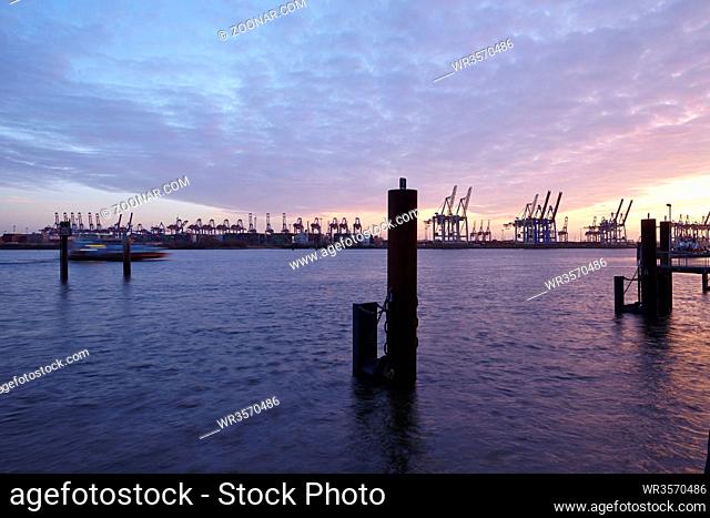 Der Hamburger Hafen am Abend mit den Containerverladebrücken als Silhouetten m Gegenlicht der Abenddämmerung fotografiert